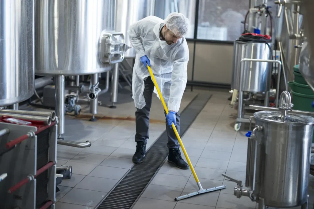 Addetto alle pulizie industriali con tuta protettiva in uno stabilimento